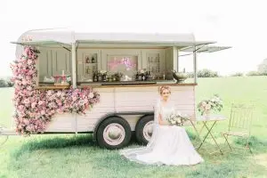 Bride on a chair in front of a converted horse box bar | Essex Wedding Planner